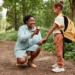 Side view portrait of black mother and daughter hiking together and using bug spray