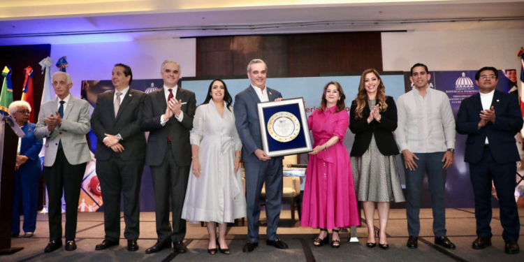 Fotografía del presidente Luis Abinader, mientras recibe reconocimiento de Gina Magnolia Riaño, Secretaria General de la OISS.