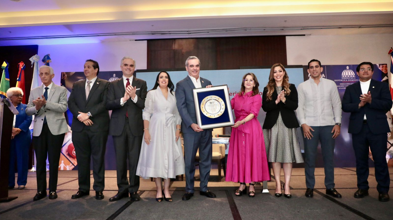 Fotografía del presidente Luis Abinader, mientras recibe reconocimiento de Gina Magnolia Riaño, Secretaria General de la OISS.